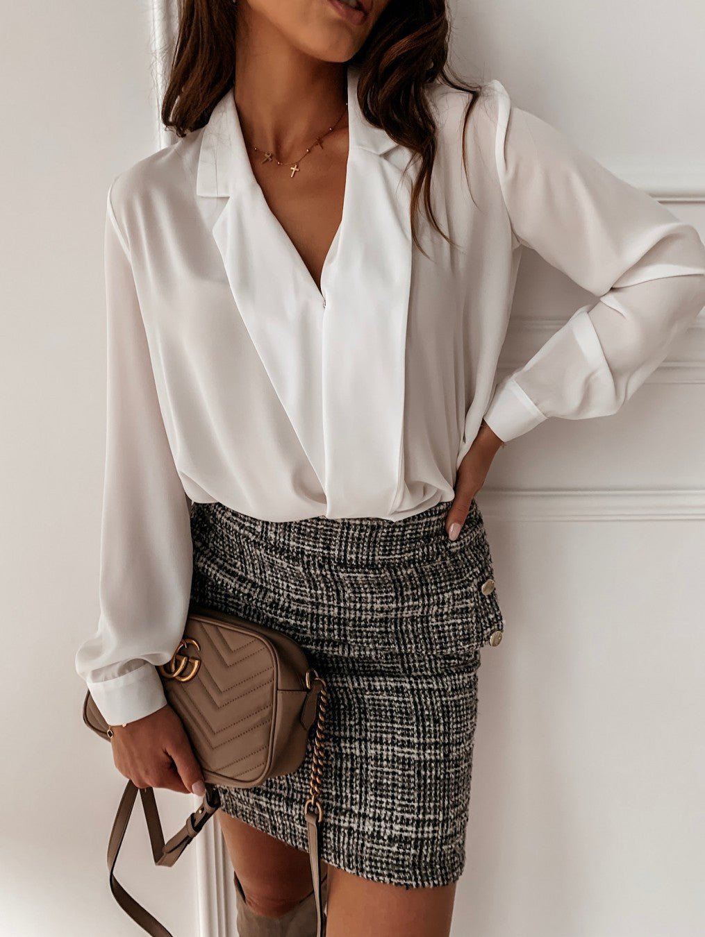 Model styling a white draped blouse with a checked skirt